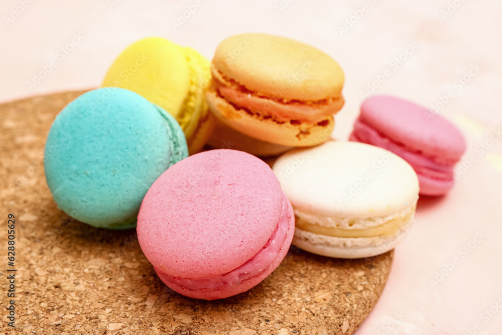 Board with sweet macaroons on pink background