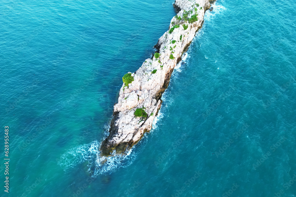 Beautiful rocky island over blue sky. A lonely beautiful island in the sea with waves. top view from