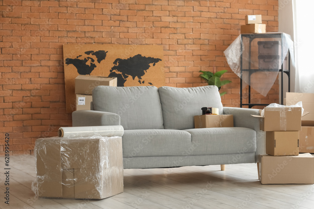 Sofa with cardboard boxes in living room on moving day