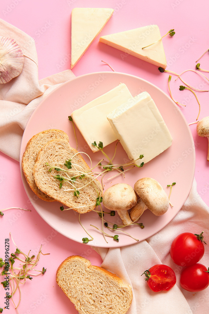 Plate with processed cheese, bread and vegetables on pink background