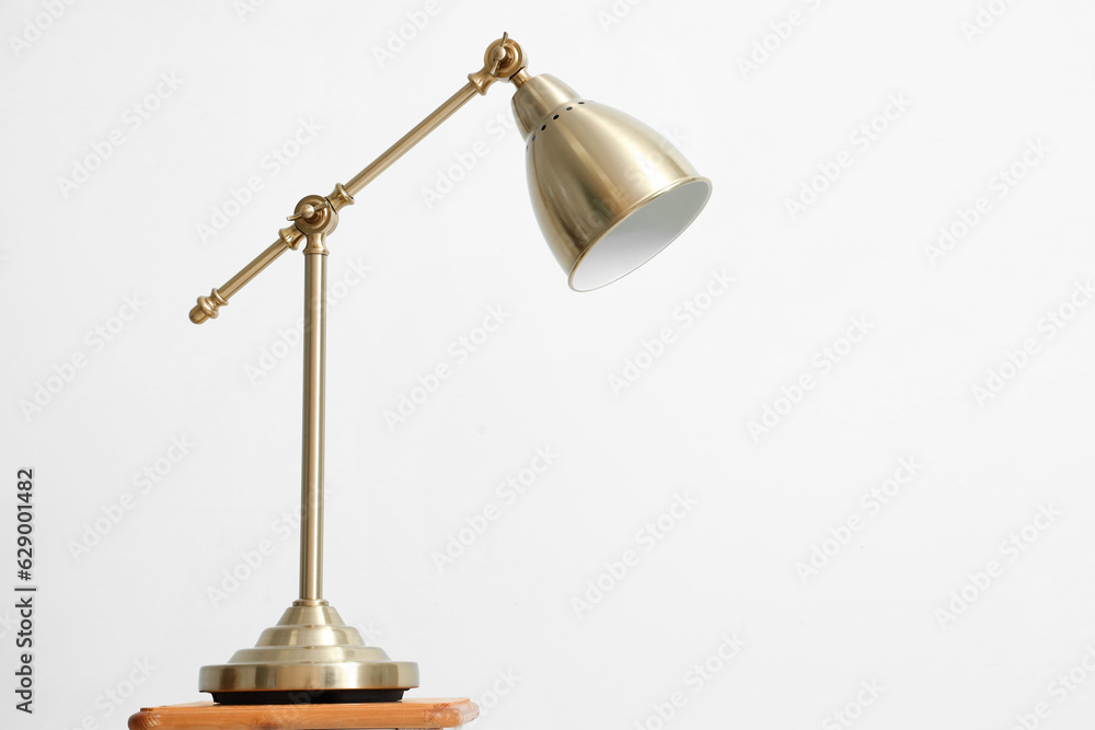 Golden lamp on table against light background