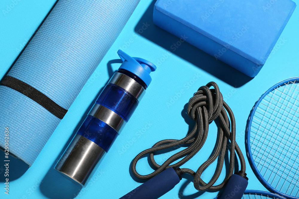 Set of sports equipment with bottle of water on color background, closeup