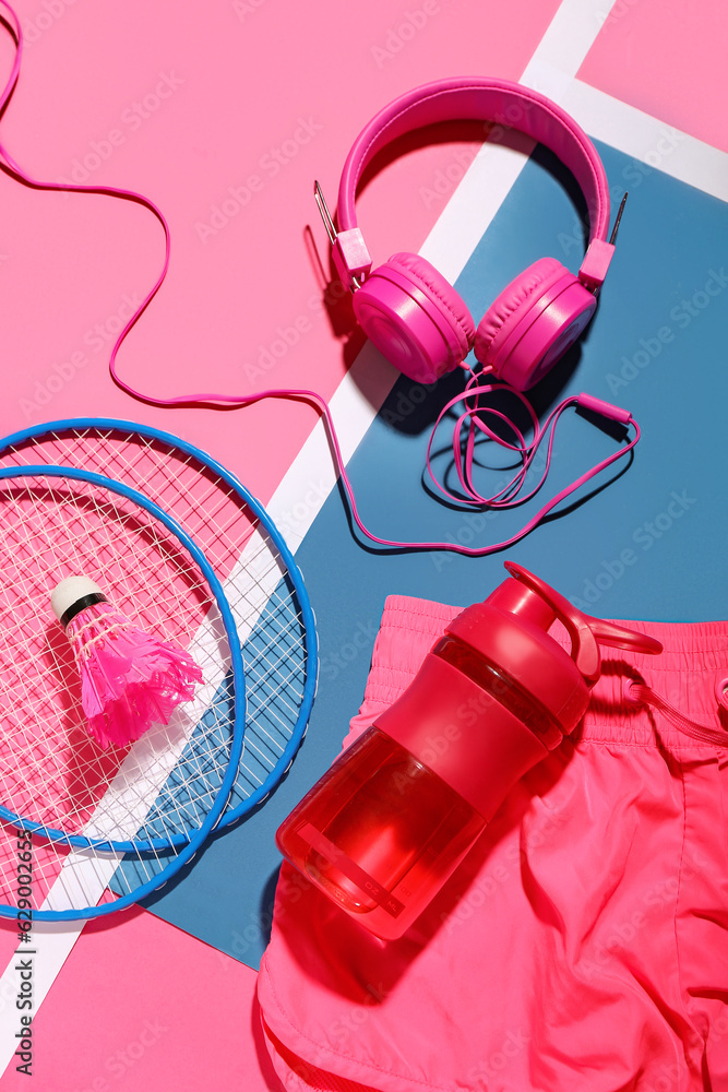 Composition with bottle of water, headphones, badminton rackets and shuttlecock on color background