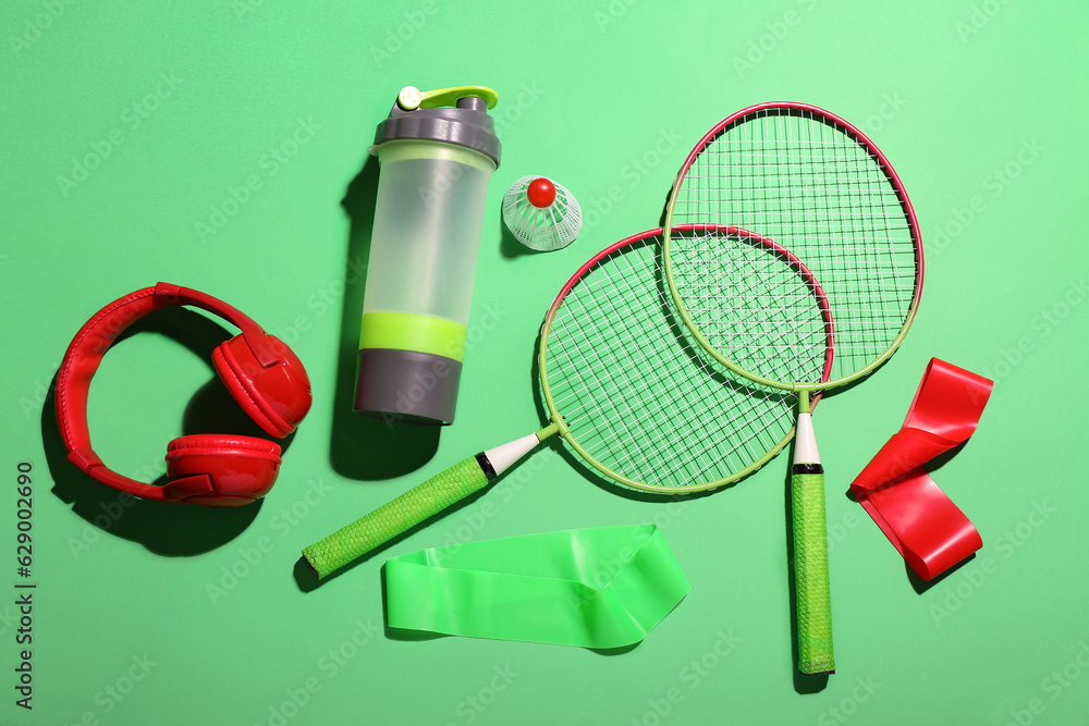 Composition with sports equipment and bottle of water on green background