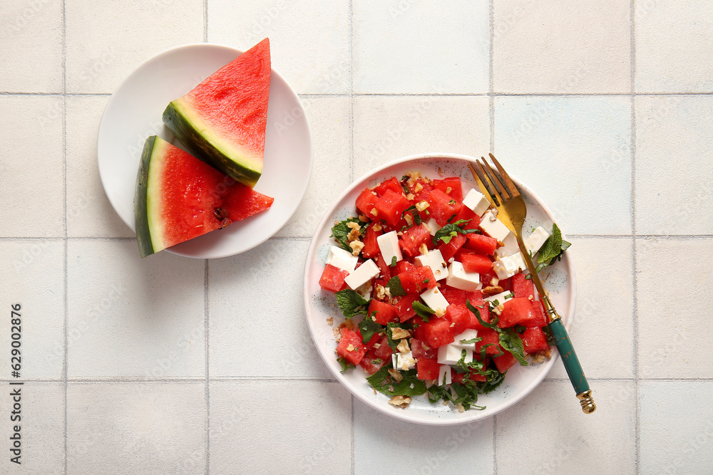 Plate of tasty watermelon salad on white tile background