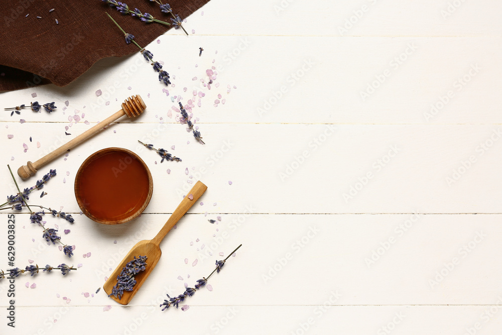 Bowl of sweet lavender honey, dipper and flowers on white wooden background