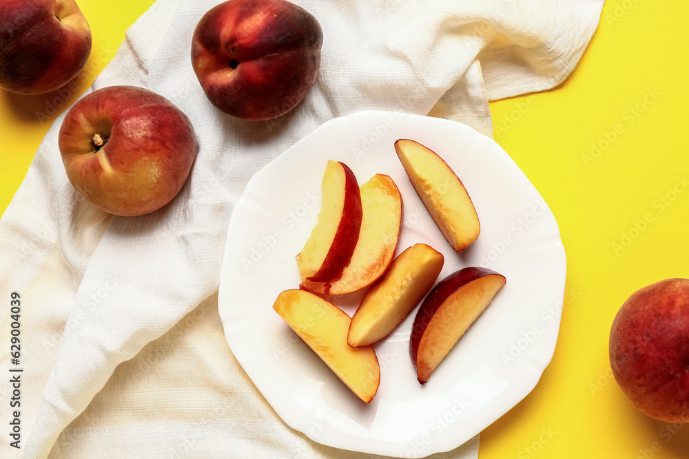 Plate with pieces of sweet peaches on yellow background