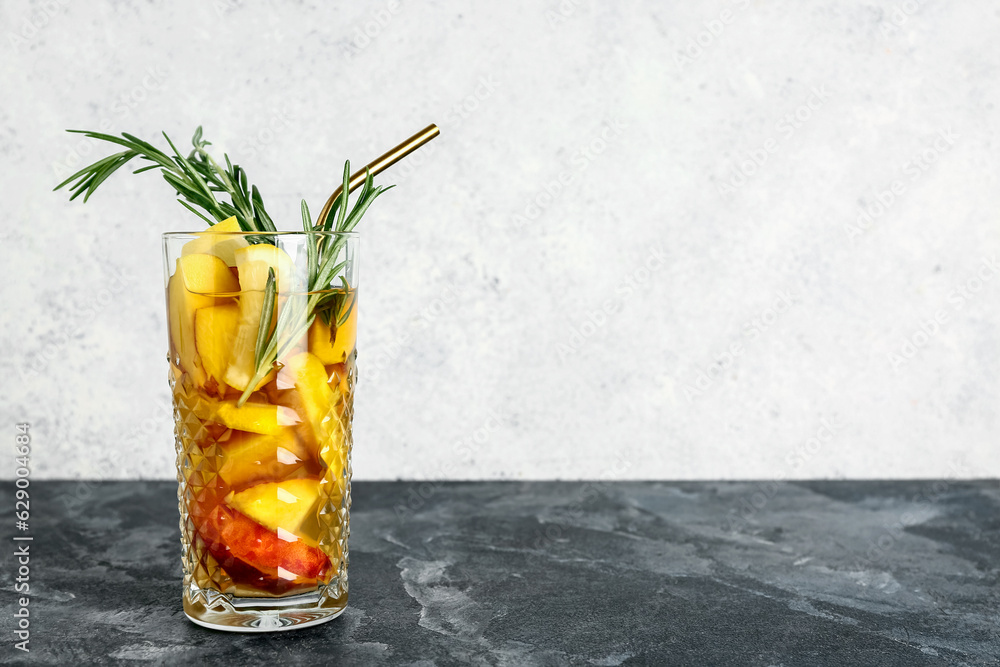 Glass of fresh peach lemonade with rosemary on blue table