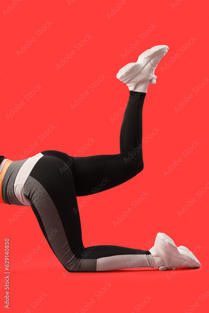 Sporty young woman in leggings on red background