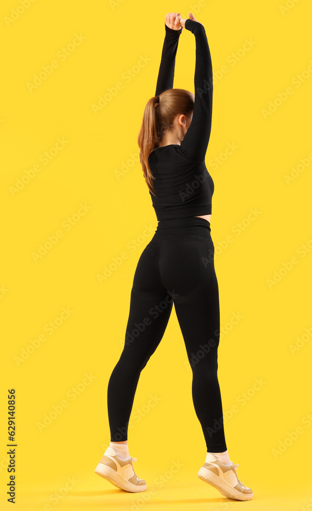 Young woman in sportswear on yellow background