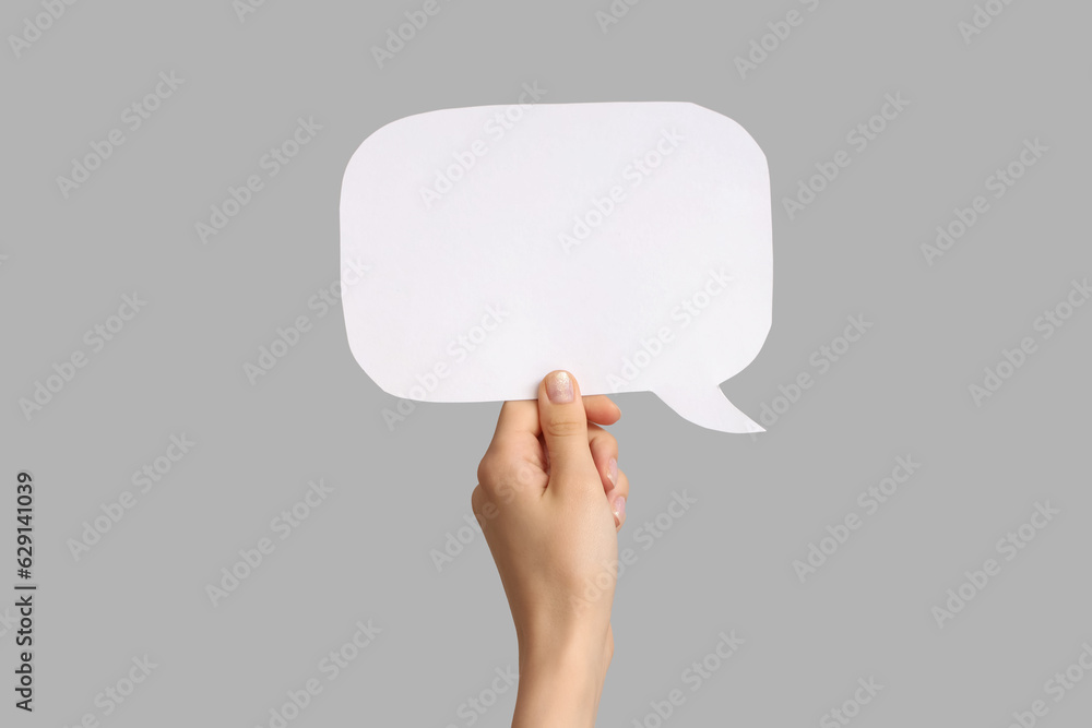 Female hand with speech bubble on grey background