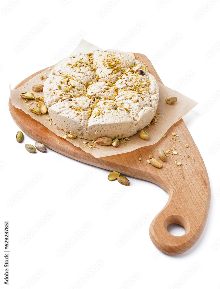 Wooden board of tasty Tahini halva with pistachios on white background