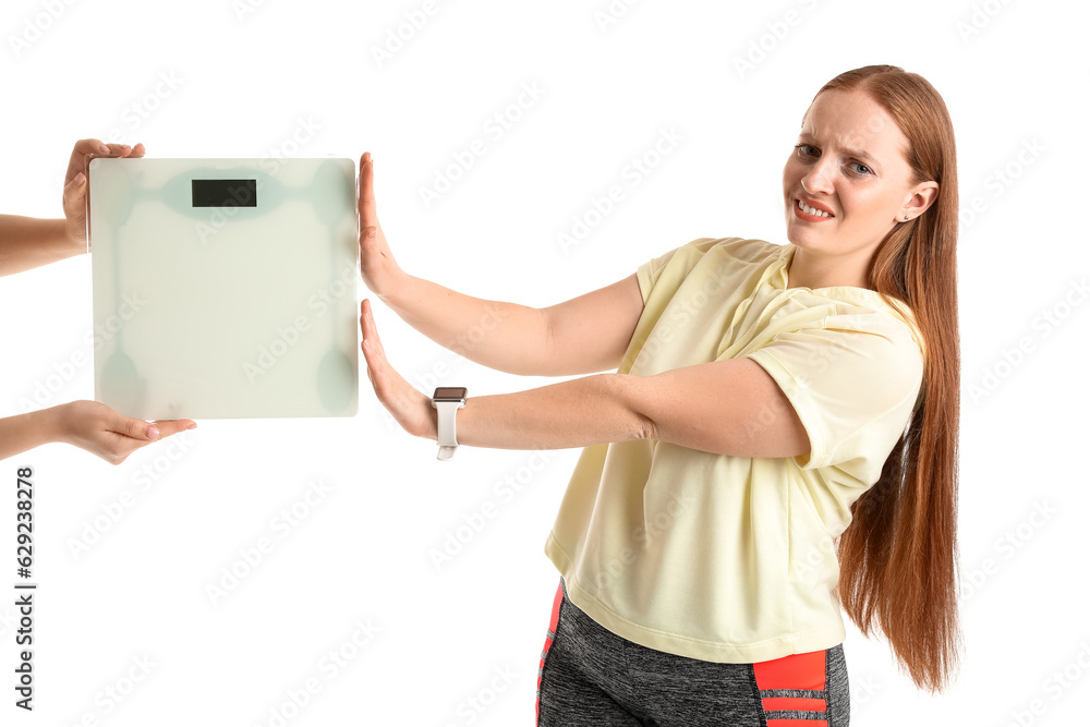 Displeased young overweight woman rejecting scales on white background