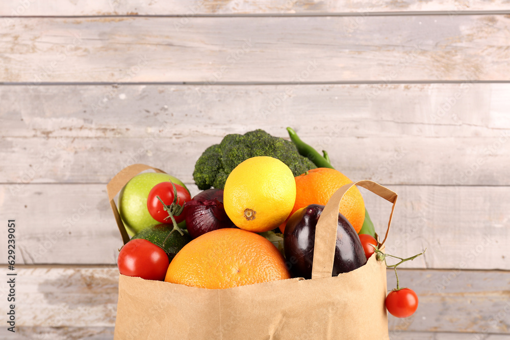 Paper bag with vegetables on wooden background