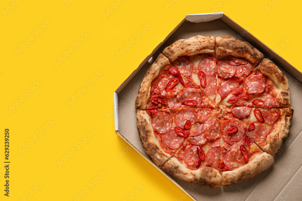 Cardboard box with delicious pepperoni pizza on yellow background