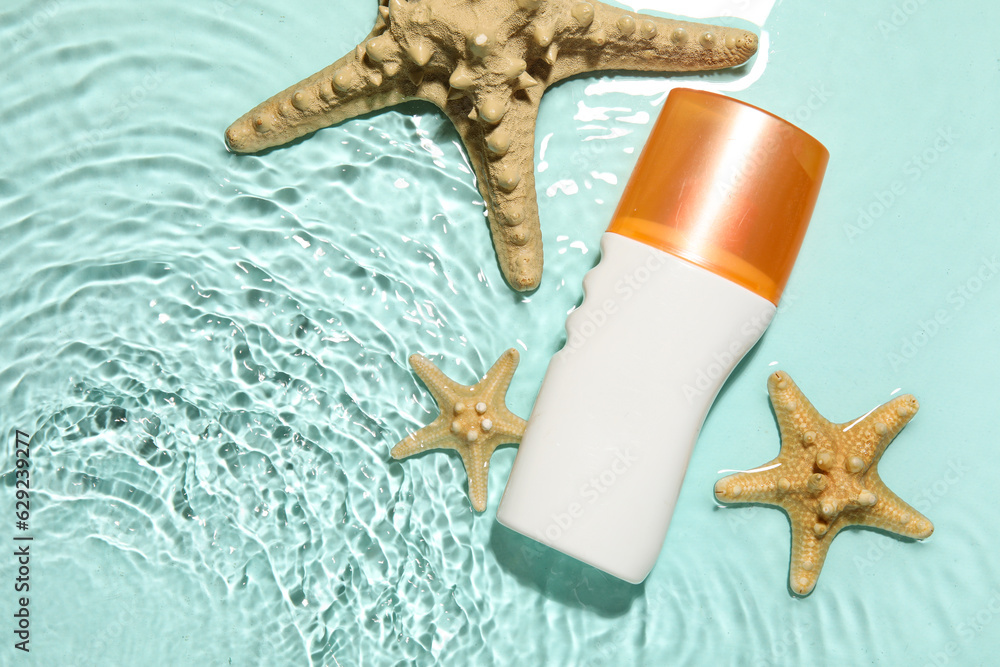 Sunscreen cream with starfishes in water on color background