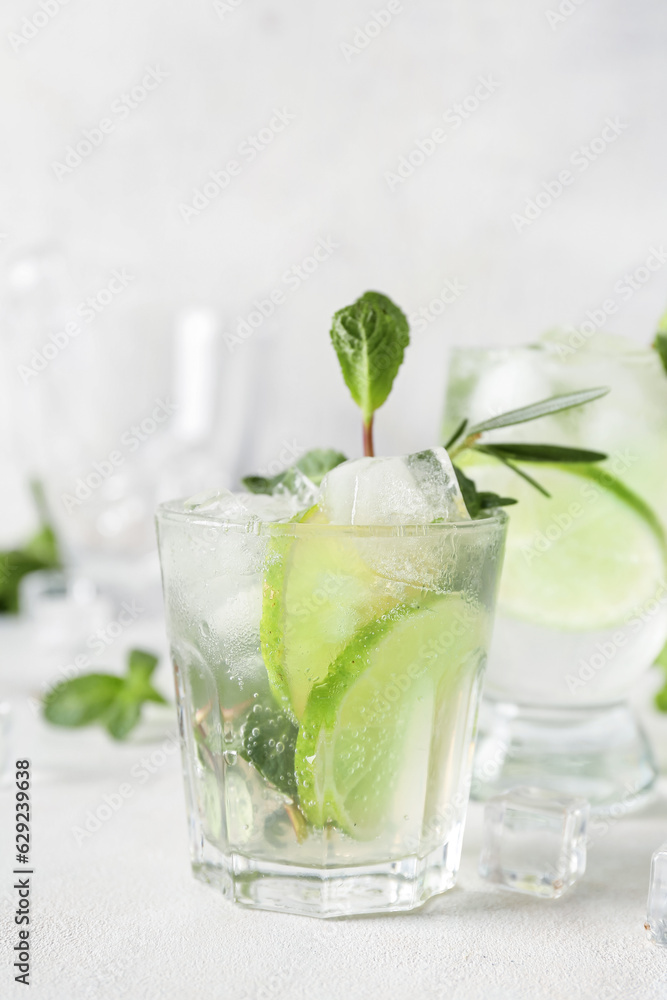 Glass of tasty mojito on light background