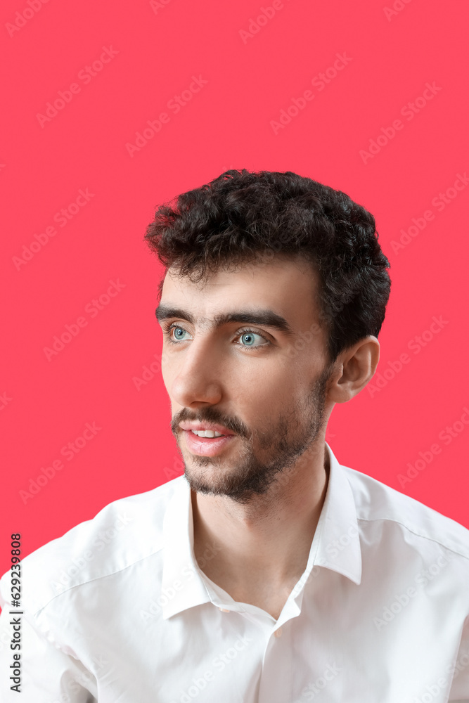 Young brunette man with stylish hairdo on red background, closeup