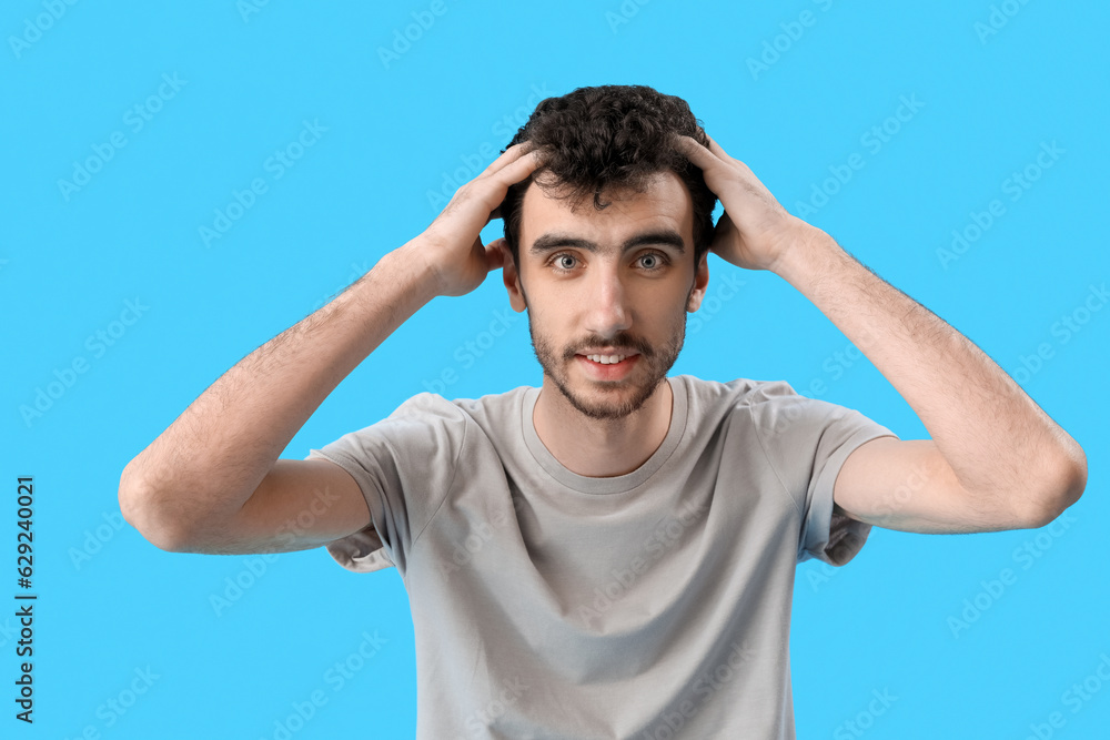 Young brunette man with stylish hairdo on blue background