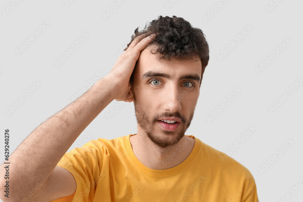 Young brunette man with stylish hairdo on light background, closeup