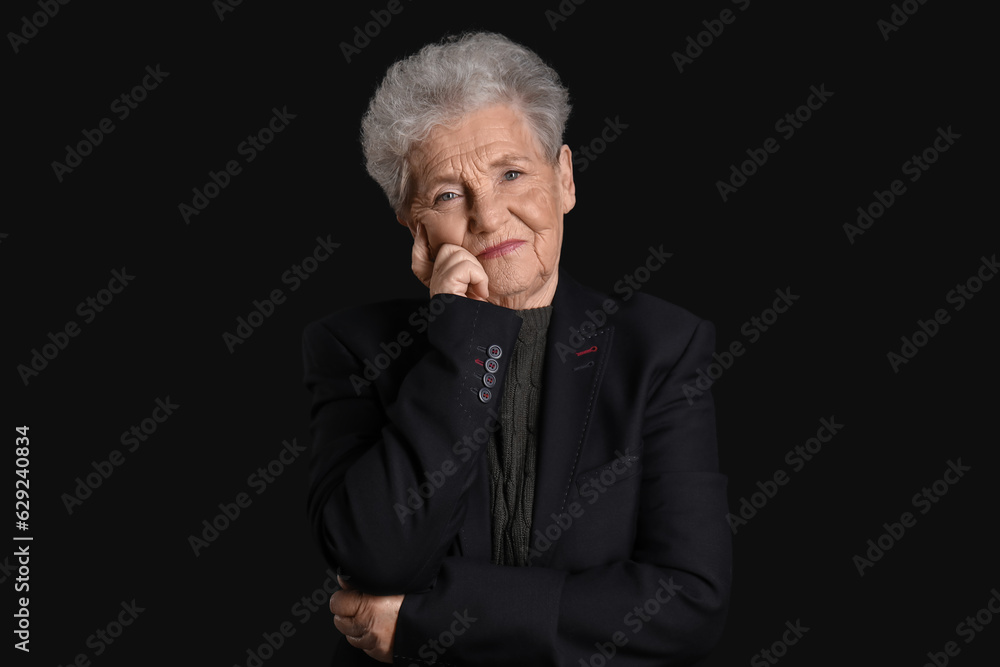 Thoughtful senior woman on black background