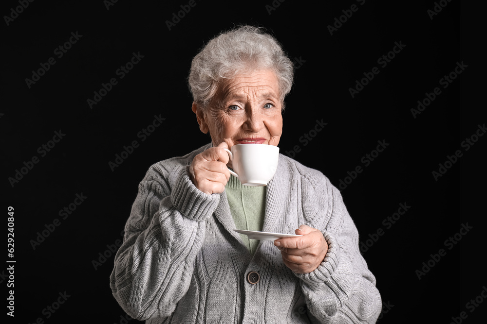 Senior woman with cup of coffee on black background