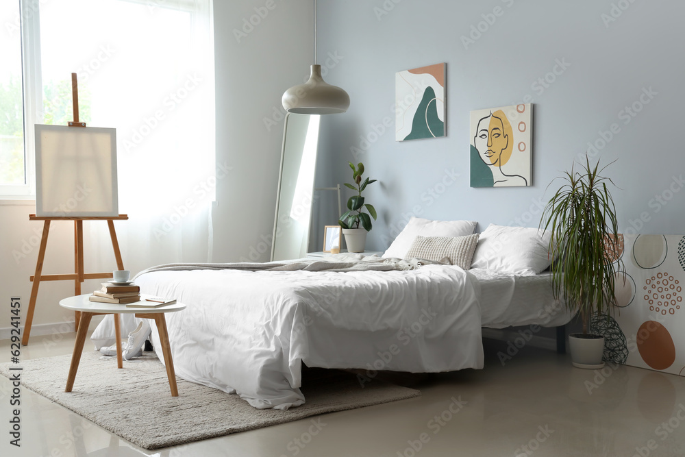 Interior of light childrens bedroom with easel and cozy bed