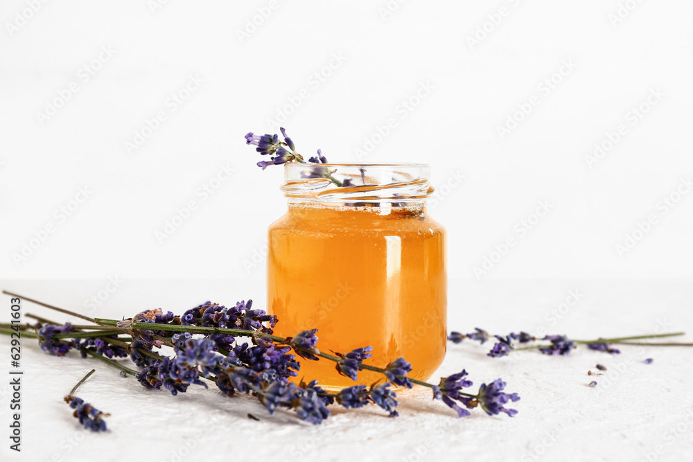 Jar of sweet lavender honey and flowers on white background