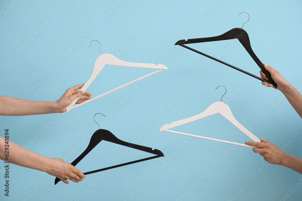 Women holding wooden clothes hangers on blue background