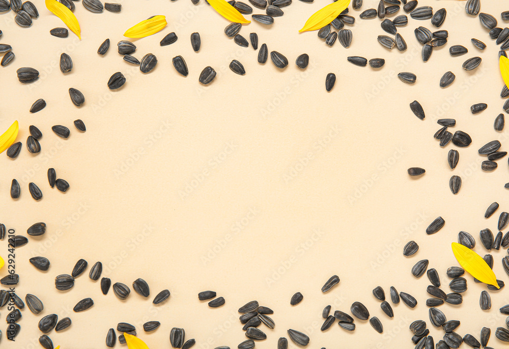 Frame made of sunflower petals and seeds on beige background