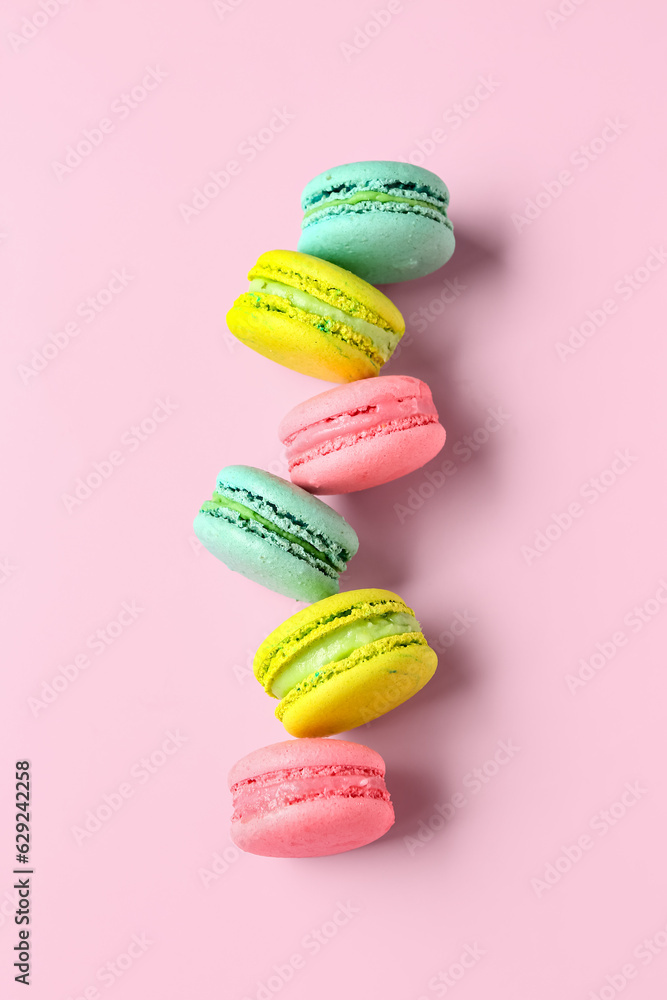 Different tasty sweet macaroons on pink background