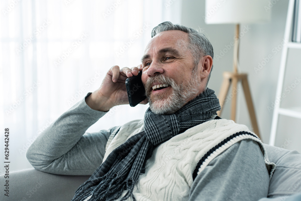 Caucasian senior elderly male using mobile phone in living room at home. 