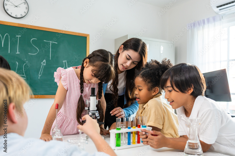 Adorable student learn with teacher in classroom at elementary school. 