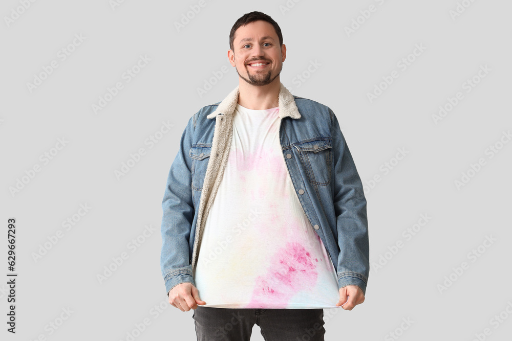 Handsome man in tie-dye t-shirt on light background