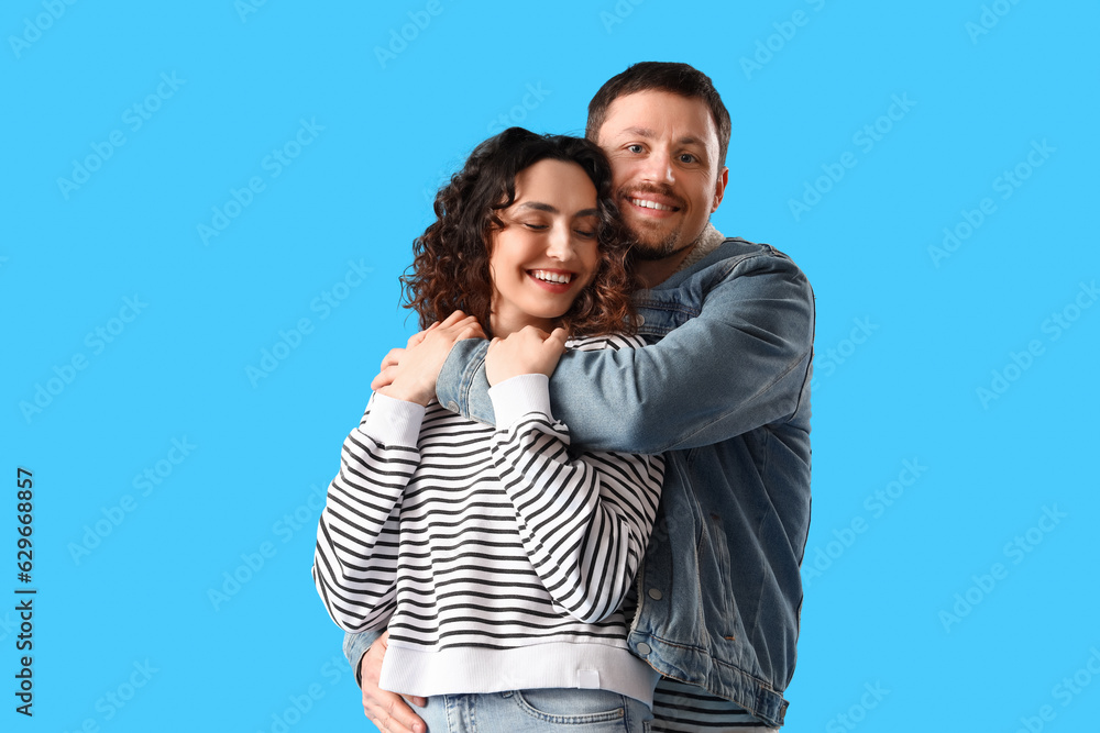 Happy young couple hugging on blue background