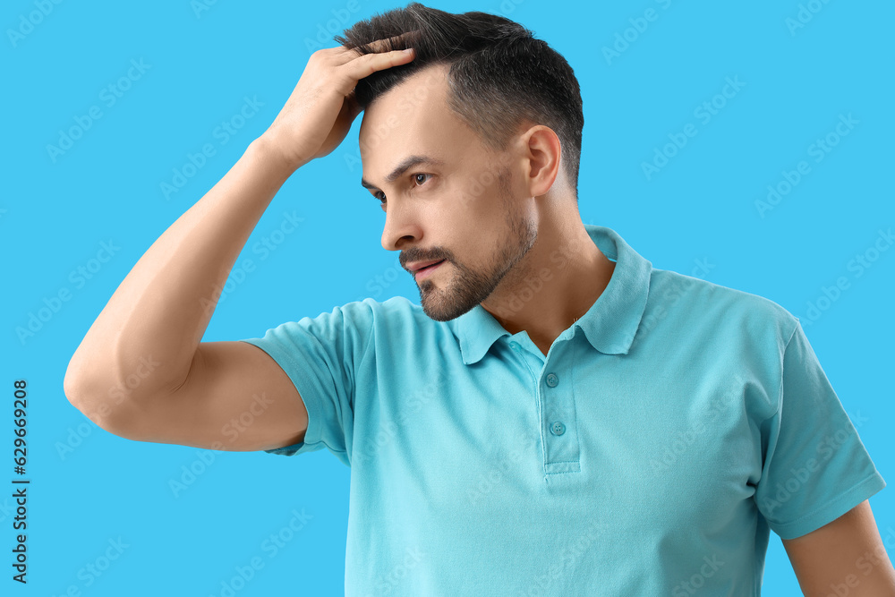 Handsome man with hair loss problem on blue background