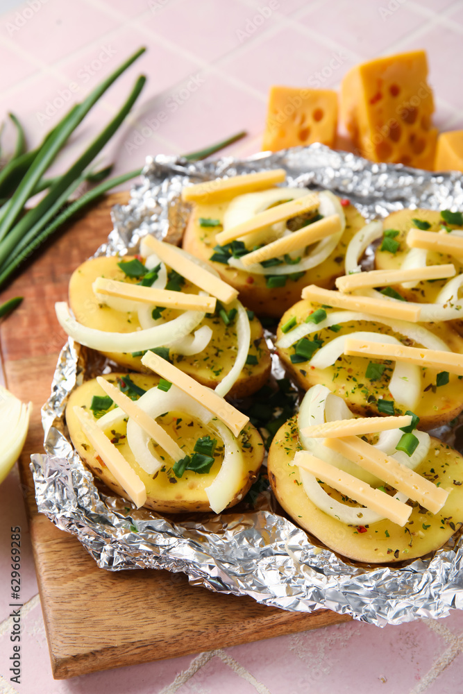 Wooden board with raw potatoes, onion, cheese and spices on table, closeup