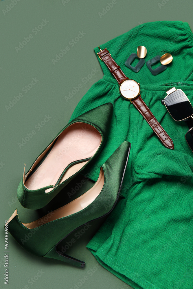 Composition with stylish heels, accessories and clothes on green background