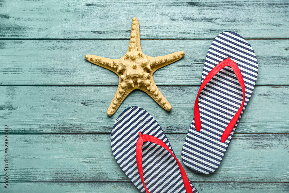 Flip-flops with starfish on blue wooden background