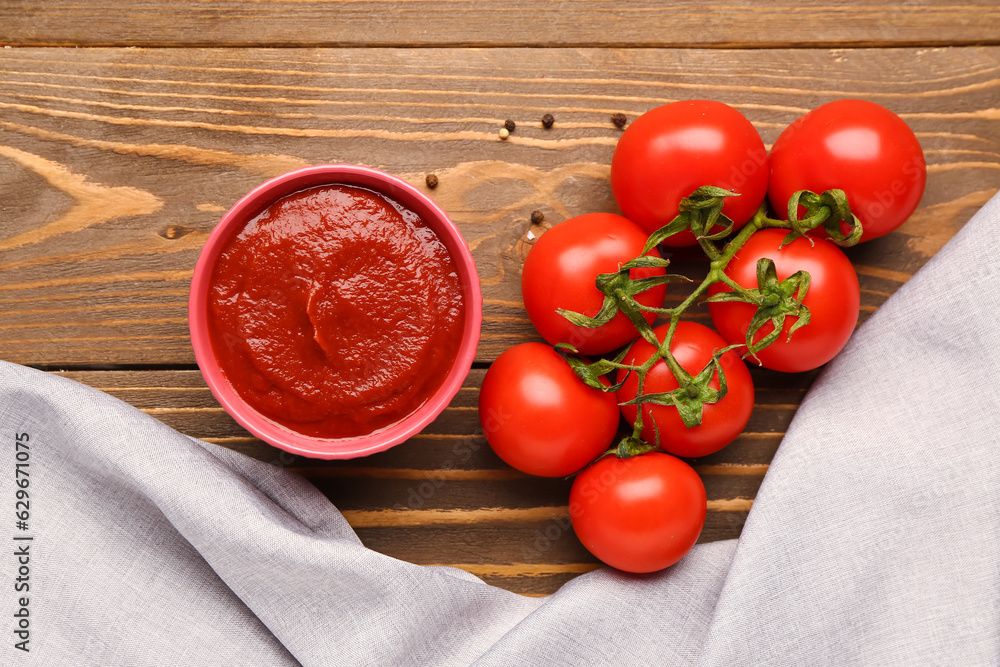 Bowl with tasty tomato paste and fresh vegetables on wooden background