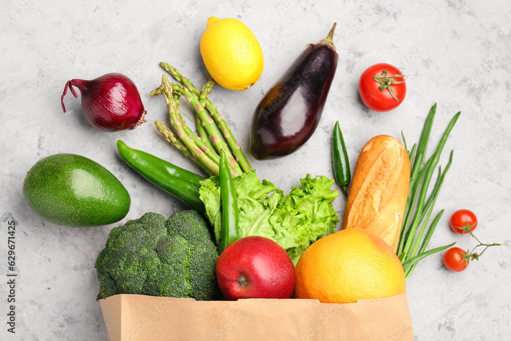 Paper bag with vegetables, bread and fruits on background