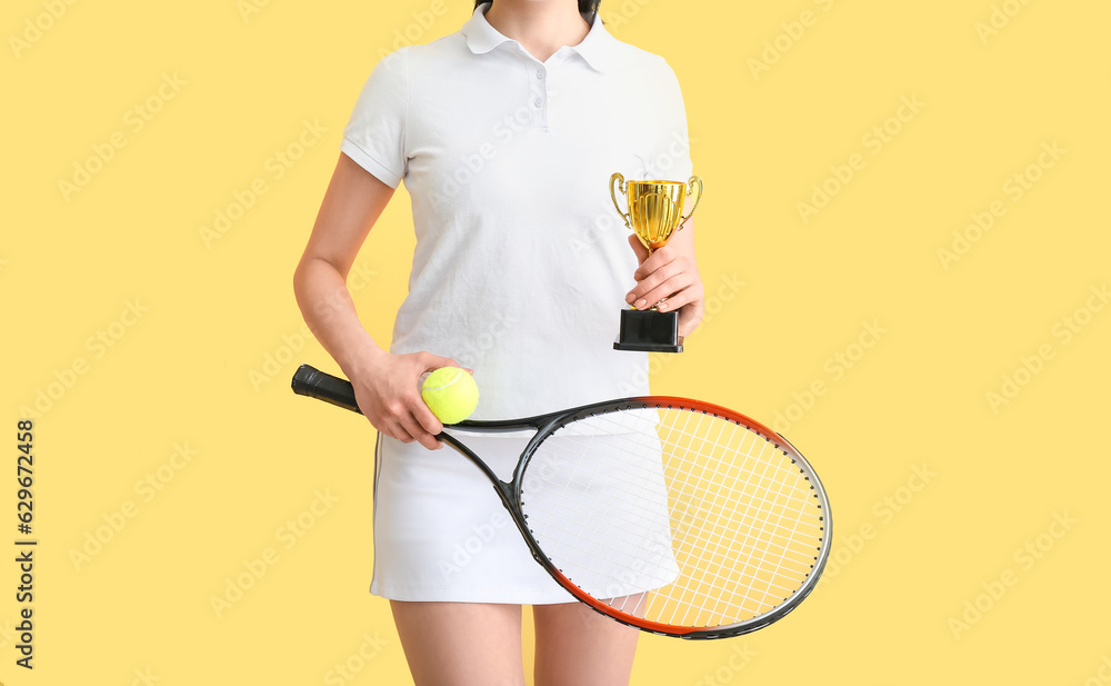 Female tennis player with gold cup on yellow background