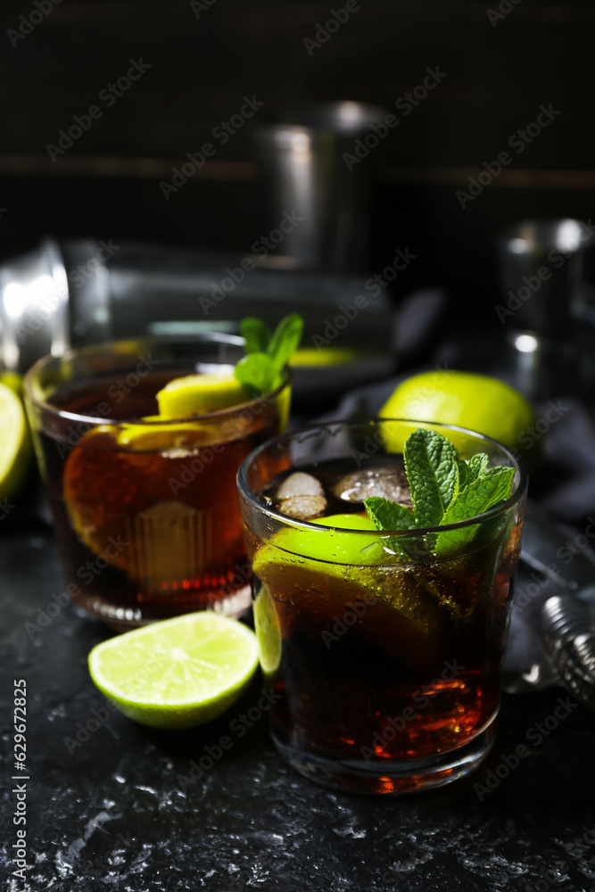 Glasses of tasty Cuba Libre cocktail on dark background