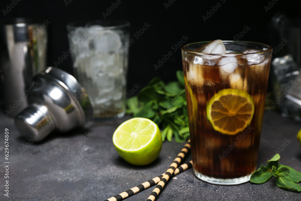 Glass of cold Cuba Libre cocktail on dark background