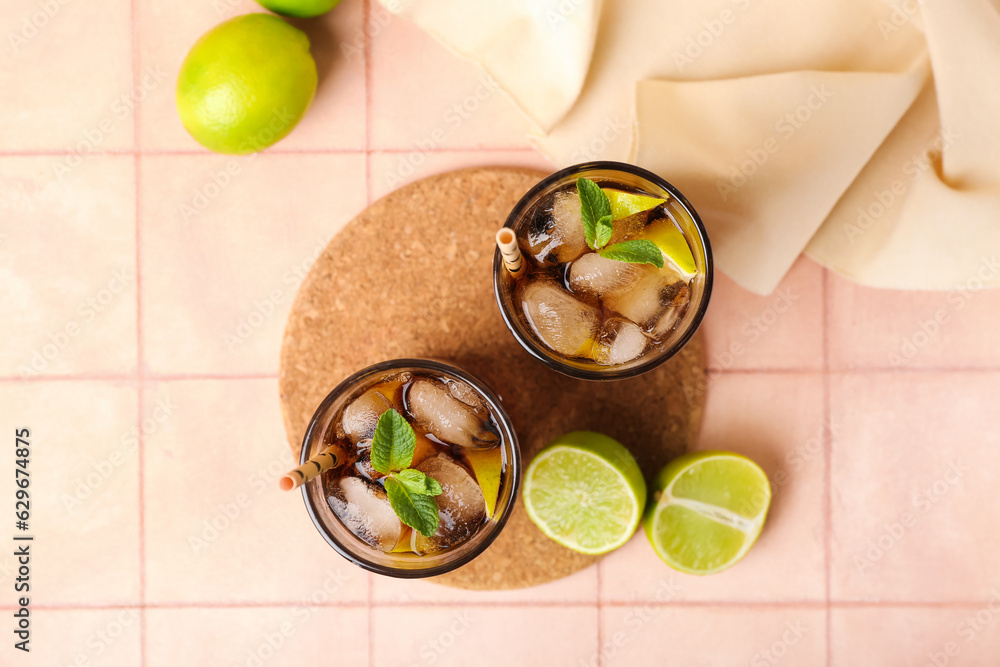 Glasses of cold Cuba Libre cocktail on light tile background