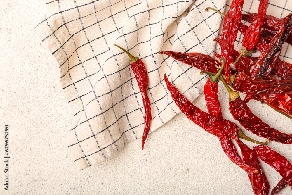 Dry hot chili peppers with checkered napkin on white background