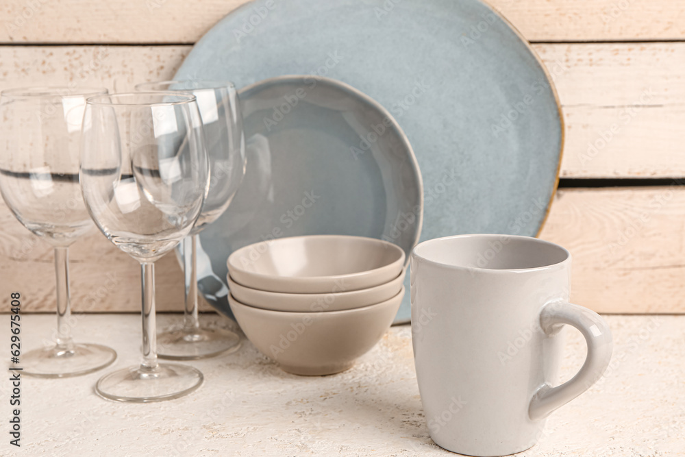 Set of different dishes on table near beige wooden wall