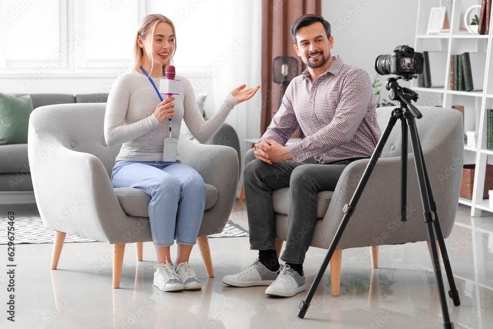 Female journalist with microphone having an interview with man in studio