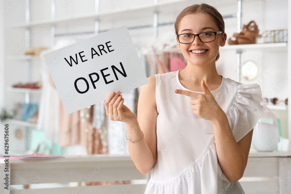 Female seller with opening sign in boutique