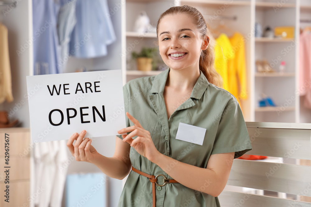 Female sales consultant with opening sign in boutique